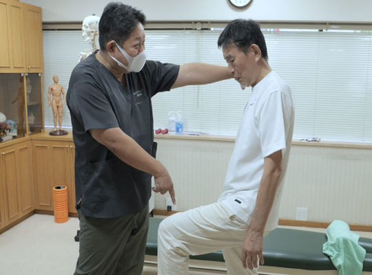 座る高齢者と療術者